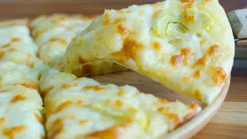 特写镜头：榴莲披萨上铺满金黄拉丝芝士与榴莲果肉，其中一片正被取起。奇葩榴莲美食，榴莲披萨。