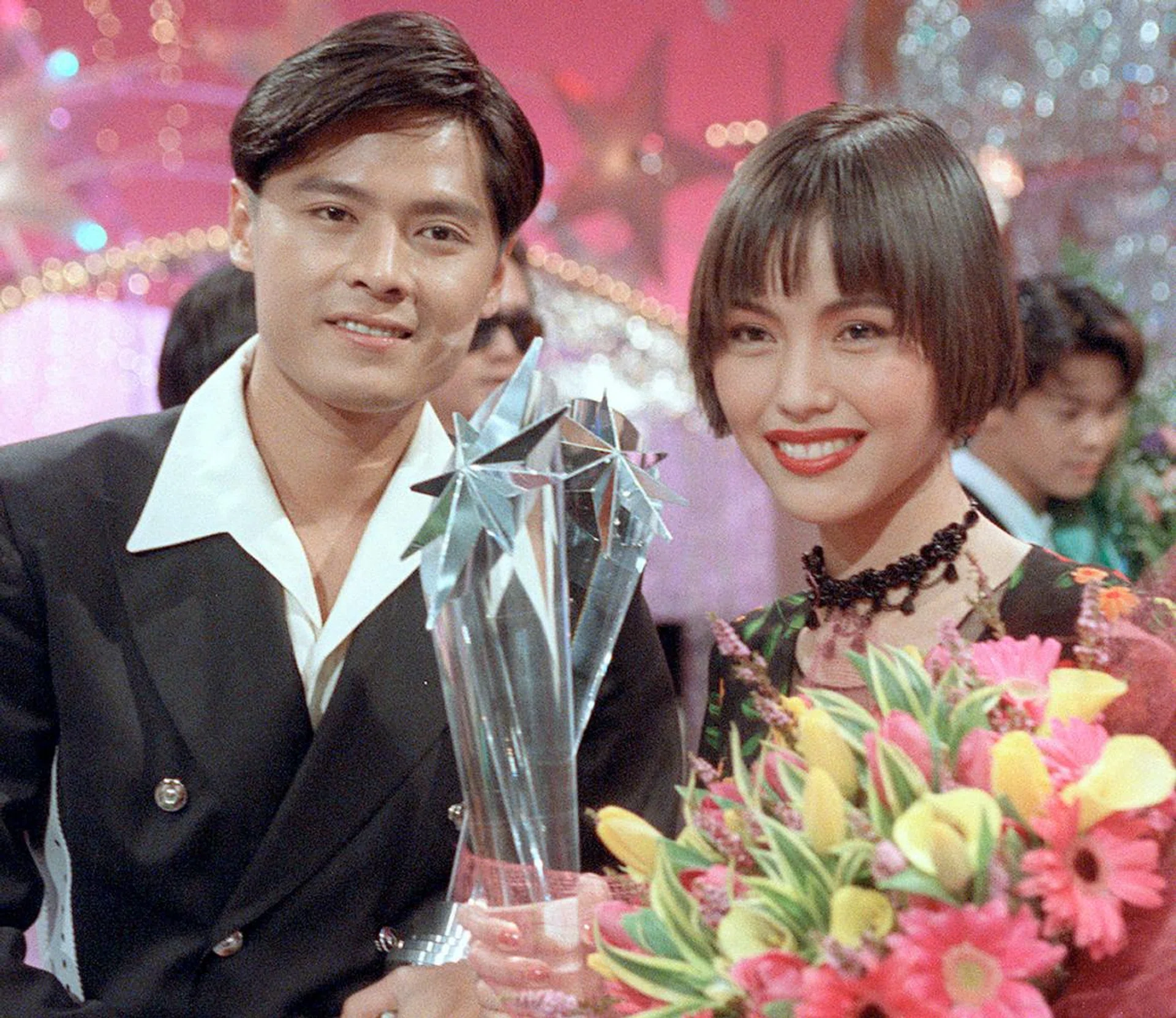 红星大奖颁奖典礼现场，两位艺人手持奖杯与花束合影，背景为灯光与舞台装饰，整体氛围喜庆而隆重。