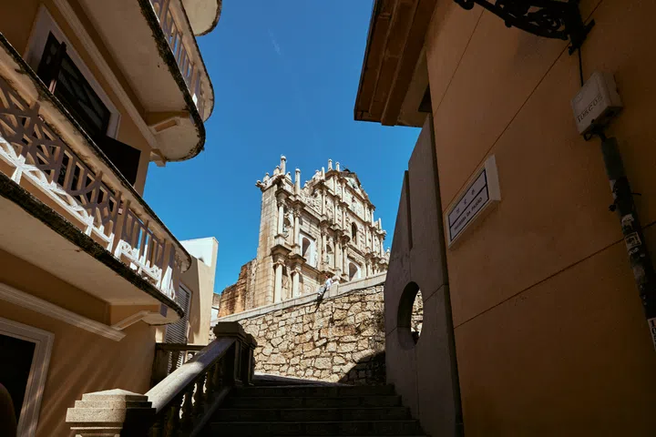 从石阶远望大三巴牌坊（Ruins of St. Paul’s），这座澳门最具代表性的地标在蓝天下格外壮丽，展现了中西建筑风格的融合之美。从恋爱巷望向大三巴牌坊（Ruins of St. Paul’s），视角清新、少人又好拍，是许多旅人心中的隐藏打卡点。澳门3天2夜旅游攻略。