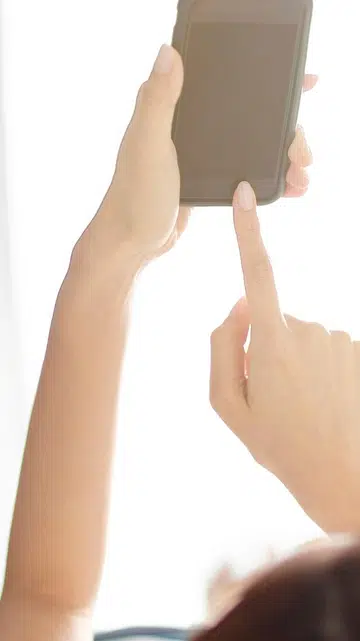 一名女生手持手机观看微短剧，画面右侧显示多部爆款中国微短剧的片单，包括《顶级偏爱！妈咪，我找到爹地了》《好一个乖乖女》《请君入我怀》《十八岁太奶奶驾到，重整家族荣耀》等。