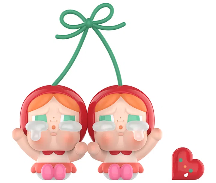 一款 POP MART Crybaby 系列玩偶模型。造型为一对连体的双胞胎角色，头上戴着红色圆形樱桃帽，两人通过绿色的樱桃梗相连。角色有橙色刘海和绿色大眼睛，脸上点缀雀斑，眼角流下夸张的白色泪水，呈现经典的“哭哭脸”表情。她们穿着红色领口的小裙子，脚上是粉色鞋子，坐姿微微举手。旁边配有一个红色的爱心小物件，上面点缀表情元素。整体形象既可爱又带着一丝心酸，展现 Crybaby 特有的“疗愈系丑萌”。POP MART Crybaby爱神的眼泪系列中的“甜在一起”。