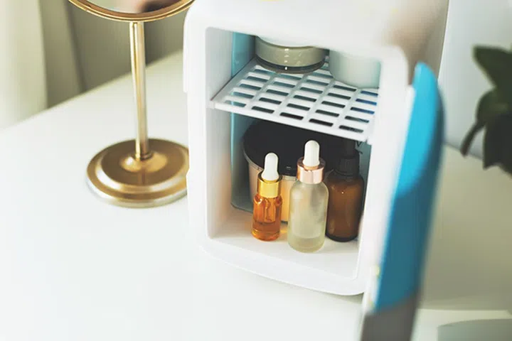 Mini fridge on the vanity table. Selfcare concept. Keep skincare, makeup and beauty product cool and fresh. Extend shelf live of creams, serums. Keep your beauty products organized and cool.