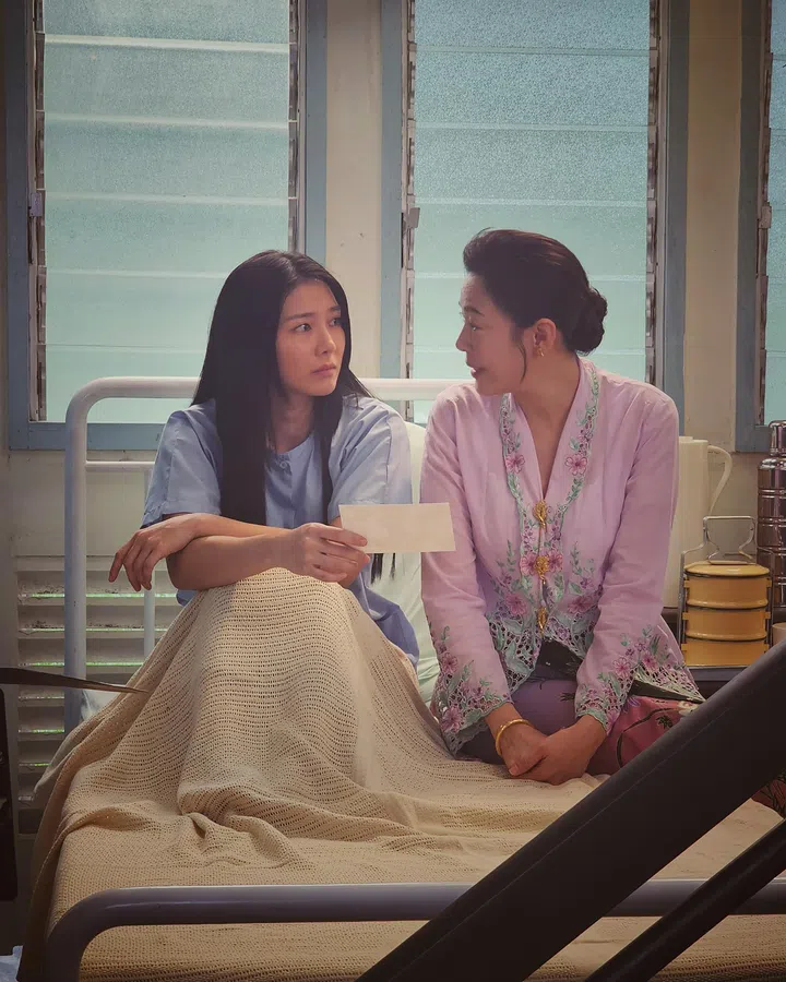 《小娘惹之翡翠山》剧照中，Ferlyn饰演的张安雅坐在病床上，与身穿粉紫色娘惹服饰的母亲淑琴并肩交谈，画面温馨安静。