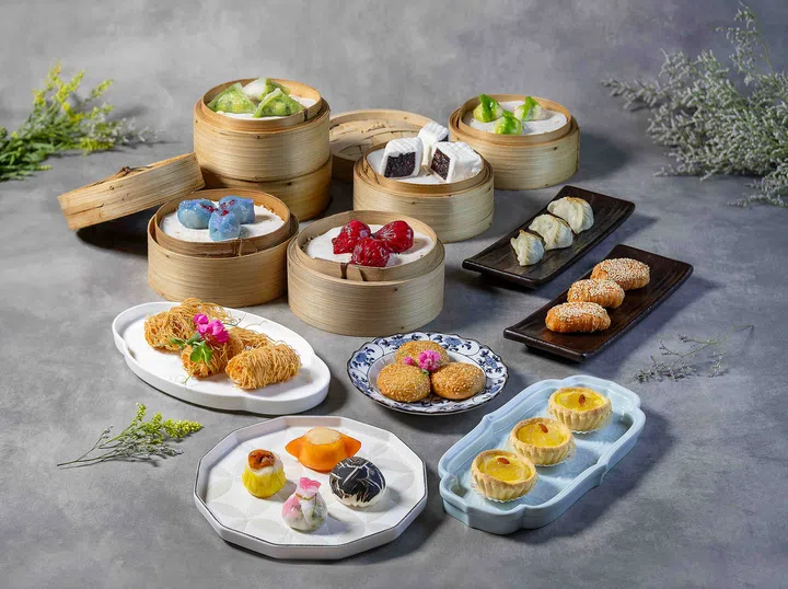 图中展示四川豆花餐厅的精致点心自助餐：多款蒸笼点心整齐排列，包括虾饺、烧卖、糯米鸡、流沙包及蛋挞等；搭配炸芋角、芝麻球和酥皮点心，色彩缤纷、造型精美，摆盘优雅。新加坡点心自助餐推荐