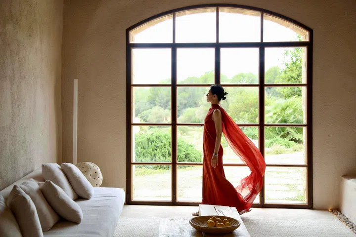 欧菁仙身穿红色长裙伫立在拱形落地窗前裙纱随风飘扬
