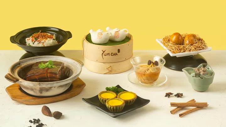 桌上摆放着Yum Cha 25周年限定茶香料理，包括茶壶造型包、乌龙茶卤蛋、水仙王焖花肉、龙井茶冻及蛋挞等，每一道都融入茶元素，呈现精致又富创意的港式风味。新加坡点心自助餐推荐