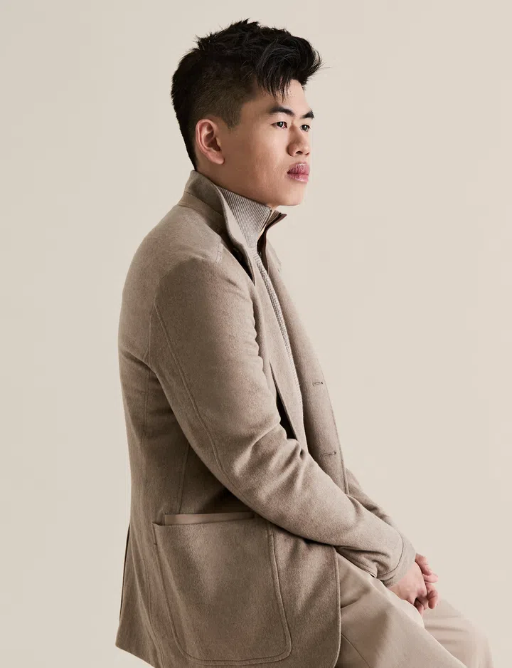 Cho Jun Ming 坐在高脚凳上侧身看向前方，神情沉稳专注，象征他从挫折中重新出发、以自学与坚持走上导演之路。本地短片和电影导演Cho Jun Ming，自学成电影导演