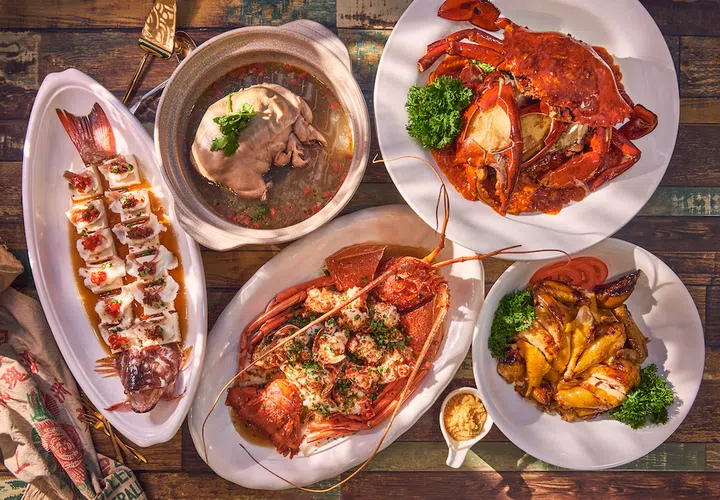 Yang Ming Seafood父母节套餐料理图：木桌上摆满丰盛海鲜与中式热菜，包括招牌龙虾、辣椒螃蟹、清蒸鱼、炖汤与烧鸡等，整体色泽鲜艳丰富，呈现热腾腾又适合多人共享的家庭聚餐氛围。2026母亲节餐厅精选指南