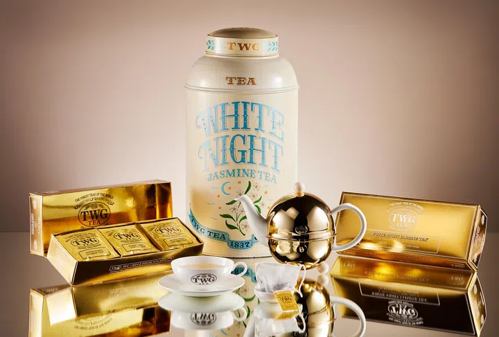 TWG Tea White Night Jasmine Tea 母亲节礼盒产品照，以奶白与金色包装呈现高级优雅质感。画面中央摆放大型 White Night Jasmine Tea 茶罐，搭配金色茶壶、TWG Tea 茶杯、棉质茶包与多盒金色包装茶叶礼盒，整体以柔和暖色调与镜面倒影营造出精致奢华氛围，展现适合作为母亲节送礼的疗愈系茶饮与下午茶仪式感。母亲节礼物推荐2026：从实用家居到时尚科技，这些礼物妈妈真的超爱！