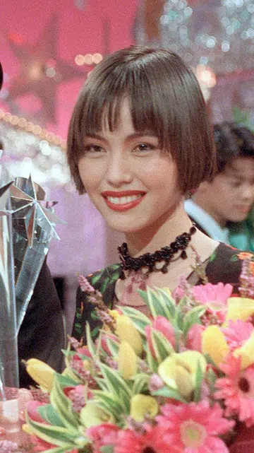 颁奖典礼现场，一名男艺人身穿黑色西装手持奖座，与一名短发女艺人并肩合影，女艺人手捧鲜花，两人面带笑容，背景为灯光闪耀的舞台装饰。李南星与郑惠玉