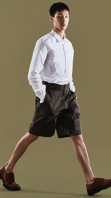 Men We Love 2025特辑封面，皮革工艺品牌 YUME 创办人 Scott Lee 身穿白衬衫与深色短裤迈步前行，展现干净利落的气质；右侧为粉色字体的标题设计。