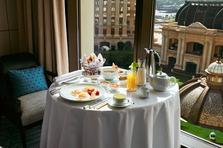 澳门上葡京酒店房内美式早餐摆设，窗外可见花园圆顶景观，是澳门3天2夜旅游攻略中推荐的住宿体验之一。澳门3天2夜旅游攻略。