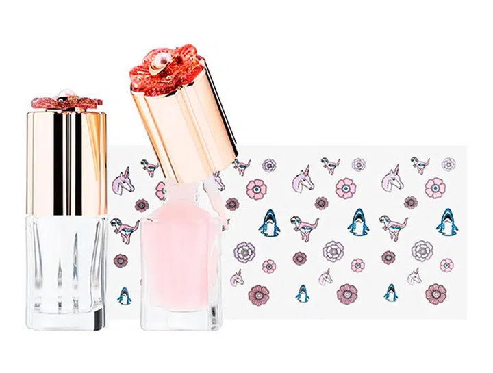 茶花作为Coach必不可少的元素，自然也出现在这回的美妆合作系列中。组合包括亮甲油和基底油（盖子上皆有茶花设计），随附的可爱恐龙、茶花、独角兽和鲨鱼等图样贴纸，也能任你在指尖上尽情发挥创意。