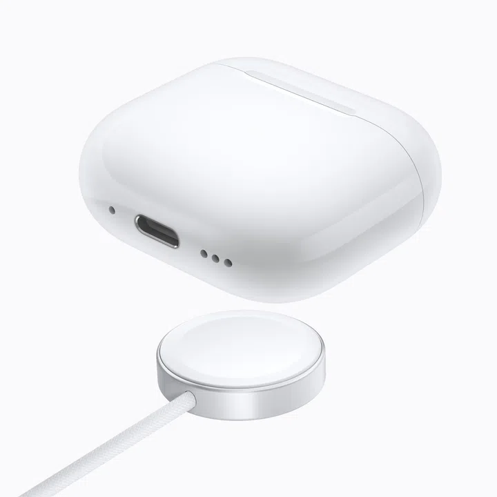 AirPods 5无线充电盒产品图，白色充电盒以关闭状态悬浮展示，底部可见USB-C充电接口及扬声器开孔。下方为圆形无线充电器，连接白色编织充电线，充电盒可直接放置其上进行无线充电，展现AirPods 5无线充电盒的充电方式与底部接口设计。