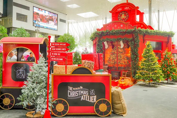 The Christmas Atelier 2024 圣诞市集布景，红色火车、圣诞树与礼物盒点缀其间，营造热闹欢乐的节日氛围。在新加坡去哪里玩？新加坡好玩推荐
