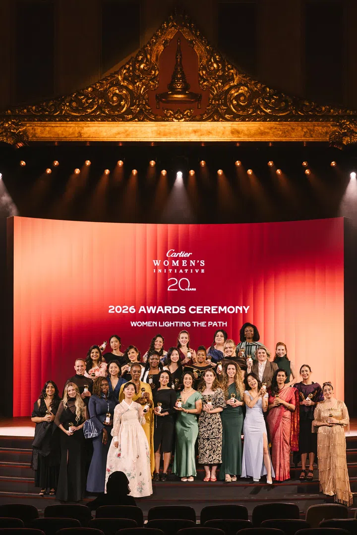 Cartier Women’s Initiative 2026 Awards Ceremony圆满结束，来自19个国家的30位女性创业者站在大型舞台中央，手持金色奖座共同合影，庆祝Cartier Women’s Initiative成立20周年。舞台背景以红橘色渐层设计呈现“2026 Awards Ceremony”及“Women Lighting the Path”主题，上方保留朱拉隆功大学大礼堂金色泰式装饰，象征国际女性创业者共同庆祝这一具有里程碑意义的时刻。