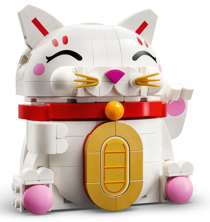 画面展示 LEGO Lucky Cat 招财猫（40813）积木摆设模型。主体为一只白色招财猫造型，脸部带有闭眼微笑表情，粉色脸颊与鼻子细节，耳朵内侧点缀红色装饰线条，整体风格可爱圆润。猫咪脖子佩戴红色项圈与金色铃铛，腹部中央镶嵌大型金色钱币造型装饰。四肢底部可见粉色圆形脚垫细节，右前爪呈举起招手姿势，营造招财寓意。整体配色以白、红、金与粉色为主，背景为纯白底，突出模型轮廓与细节。这款积木摆设适合作为农历新年或日常居家空间的装饰，也常被视为象征好运与财富的吉祥摆件。