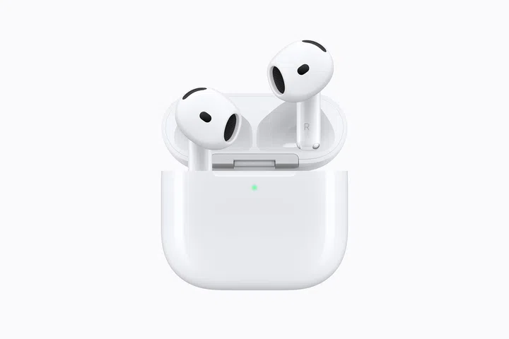 AirPods 5产品图，两只白色无线耳机从开启的充电盒中露出，采用开放式入耳设计，耳机上可见黑色扬声器网孔与感应区域，耳机柄底部带有金属触点。白色充电盒正面中央亮起绿色状态指示灯，整体以简洁的浅色背景呈现，突出AirPods 5的耳机外形与充电盒设计。