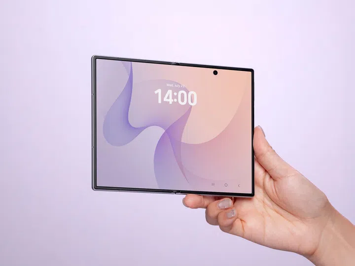 一只手单手握持展开状态的Samsung Galaxy Z Fold8，展示大尺寸内屏设计。手机采用极窄边框，内屏显示淡紫色与粉橘色渐层桌布，画面中央显示时间14:00，顶部可见置中的前置镜头开孔。展开后的宽阔屏幕呈现接近平板电脑的视觉比例，突显适合多任务处理、阅读文件、浏览网页及观看影音内容的大屏幕优势。背景采用淡紫色渐层搭配柔和灯光，整体画面简约现代，进一步衬托Galaxy Z Fold8轻薄机身、折叠屏幕及沉浸式显示效果。
