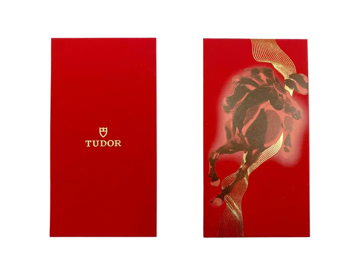 TUDOR 2026马年红包封正反面设计展示，红包封整体采用经典纯红色底色，呈现简约而富有质感的视觉效果。正面中央印有TUDOR品牌标志与盾牌徽章，采用金色烫印工艺，展现品牌一贯的低调优雅风格。背面则以动态骏马图案为视觉焦点，骏马以奔跃姿态呈现，搭配金色流线纹饰，从马身延伸而出，营造速度与动感的视觉效果，同时象征马年所代表的力量、前进与突破。整体设计融合极简品牌美学与农历新年寓意，在传统节庆元素中注入现代与精致感，体现品牌对细节与工艺的重视。2026马年红包封盘点：今年的新年红包设计，你最喜欢哪一个？