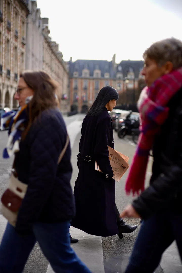 在人群中，欧菁仙夹着报纸从巴黎街头走过