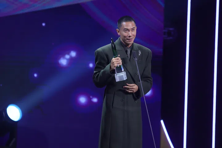 《红星大奖2026》现场，陈泂江身穿深色西装手持奖座在台上发表感言，站在聚光灯下神情激动，背景灯光璀璨，记录他荣获最佳男主角的高光时刻。《红星大奖2026》从“听牌”晋升超级红星的陈泂江