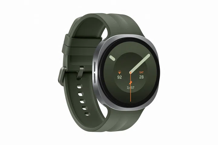 Samsung Galaxy Watch9产品展示图，采用银色圆形表壳搭配深绿色运动表带。手表以斜侧角度呈现，可清楚看见金属表壳、圆形触控屏幕及柔软硅胶表带设计。表盘采用简约指针式介面，显示时间、日期、步数、健康数据及活动资讯，整体配色以深绿色、银色及橘色点缀，风格简洁现代。背景为纯白色，突显Galaxy Watch9轻巧机身、圆形设计及兼具日常佩戴与健康管理功能的智能手表外观。