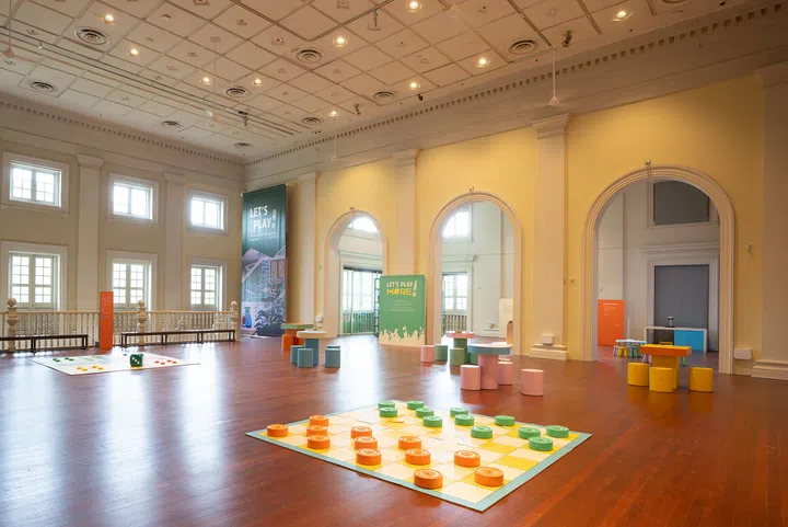 展览现场照片：亚洲文明博物馆《Let’s Play!》中的大型互动棋盘与彩色圆凳装置，空间明亮开阔，布置充满趣味。在新加坡去哪里玩？新加坡好玩推荐