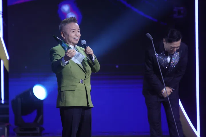 《红星大奖2026》现场，陈建彬身穿绿色西装手持奖座在台上发表感言，手持麦克风幽默致辞，台下气氛轻松热烈，记录他再度获奖的精彩瞬间。《红星大奖2026》陈建斌拿下第六座“十大”奖项，获奖时笑喊“干妈，I love you deep deep！”引来全场笑声不断。