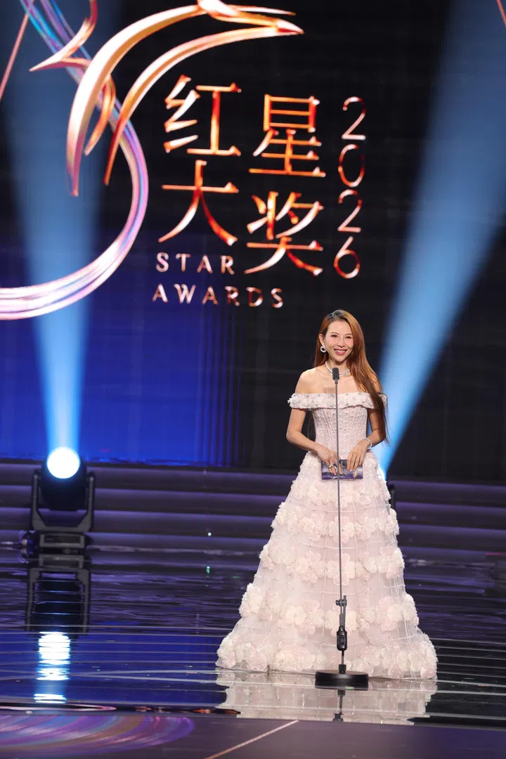 《红星大奖2026》颁奖嘉宾蔡少芬身穿优雅粉色礼服亮相舞台，在聚光灯下从容发言，背景标志醒目，现场氛围华丽而庄重。《红星大奖2026》“十大”颁奖嘉宾蔡少芬