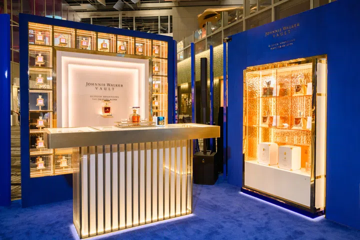 Johnnie Walker Vault 期间限定店内部陈设，金蓝配色展柜陈列多款威士忌酒瓶，灯光温暖雅致，展现奢华氛围。在新加坡去哪里玩？新加坡好玩推荐
