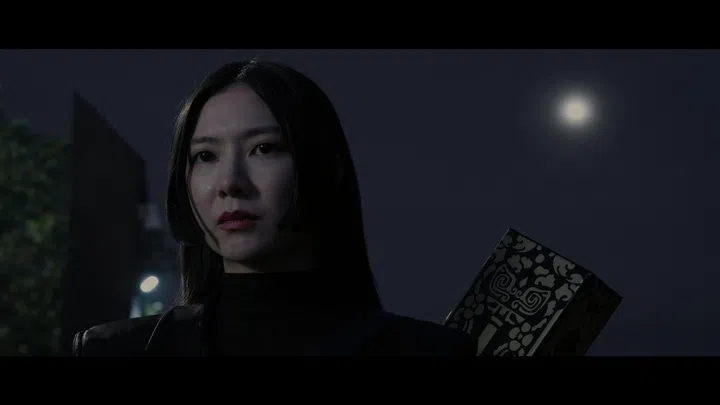 《带剑女孩》第一集剧照中，Ferlyn饰演的化成风身穿黑色造型，在夜色中神情冷静坚定，背后可见带有纹样的武器。