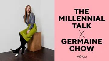 画面左侧，一位女性坐在木质方块上，背景为简洁的浅灰色墙面与深色木地板，整体风格干净利落。她留着一头顺直的长发，妆容精致，神情自信从容，微微侧身面对镜头。穿着带有微闪质感的灰色长袖上衣，搭配亮绿色高腰半裙、黑色丝袜与黑色高跟鞋，整体造型时尚且具有鲜明个性，呈现出现代女性的优雅与力量感。右侧为粉色背景，上面以黑色大字写着“The Millennial Talk X Germaine Chow”，下方为《女友》（NÜYOU）标志，整体视觉简洁鲜明，突显人物专访主题。