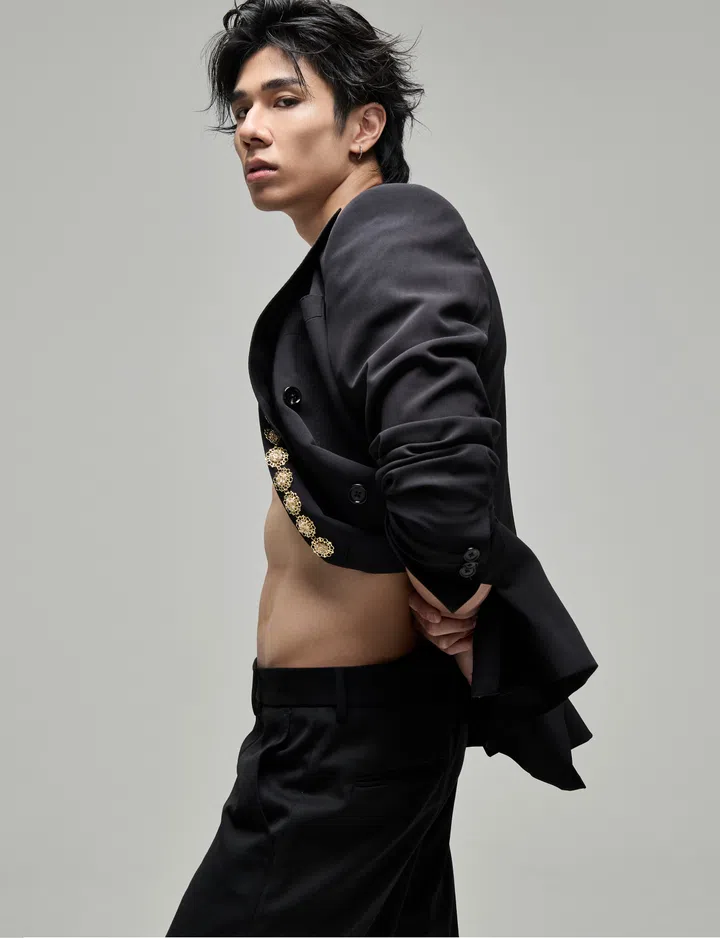 侧身而立的Why Lucas身穿Dolce&Gabbana黑色西装外套与长裤，外套微微敞开，腰腹线条若隐若现。