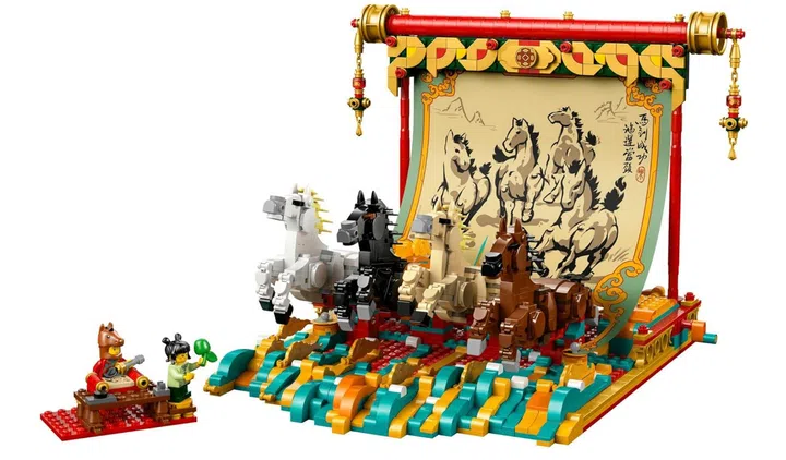 画面展示 LEGO“骏马奔腾图”（Galloping Horse Canvas，80119）积木套装完成后的立体场景。前景是一组由积木拼搭而成的多匹骏马模型，颜色包含白色、黑色、浅棕色与深棕色，排列成奔跑姿态，仿佛向前冲刺。底座以蓝绿色与金色积木拼接，呈现波浪状纹理，营造动态流动感。后方竖立一幅大型卷轴式画轴结构，画面印有水墨风格的群马图与书法文字，上方装饰红色横杆与金色细节，两侧垂挂中式流苏饰件。左侧还可见两个人偶角色与小型展示底座，增添场景故事感。整体色彩丰富，融合传统东方水墨意象与积木立体结构，适合作为农历新年或居家空间的展示摆设。