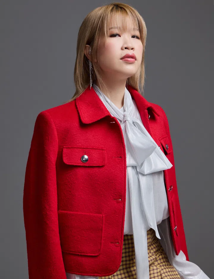 本地创作歌手Lin Ying身穿HUGO白色蝴蝶结衬衫、红色夹克与格纹裙，搭配Swarovski水晶耳饰。