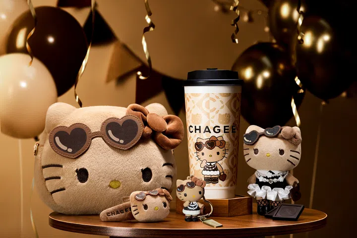CHAGEE 与 Sanrio Hello Kitty 联名系列陈列照，画面展示 Cocoa Oolong Milk Tea 节日限定杯身，以及多款 Hello Kitty 毛绒周边与吊饰，包括戴着墨镜的公仔、钥匙扣与小包，整体以暖棕色调与节日装饰为背景，呈现兼具可爱与收藏价值的限量联名商品，适合喜爱角色联名与节日限定周边的读者。