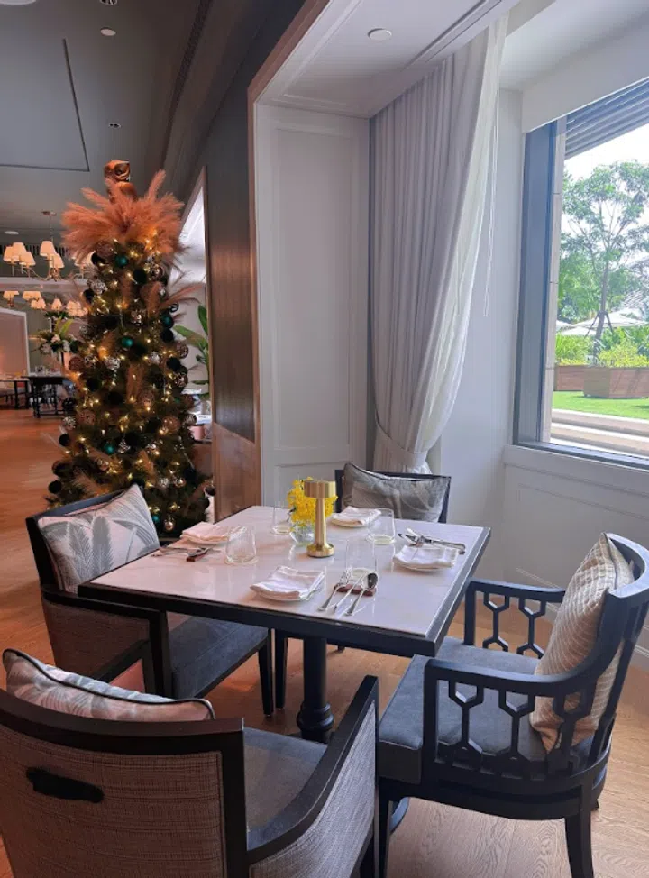 Laurus Table 餐厅内部空间照，位于新加坡圣淘沙 The Laurus, a Luxury Collection Resort。画面呈现明亮的黄色餐厅设计、开放式吧台与整齐排列的木质座位，整体氛围温馨而有质感，适合好友聚会、轻松用餐与拍照打卡。|新加坡最值得打卡的高颜值聚餐好去处