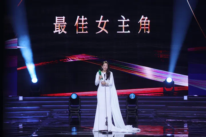 《红星大奖2026》最佳女主角得主刘子绚身穿白色长礼服站在舞台中央发表感言，手持奖座，背景大屏幕显示“最佳女主角”字样，灯光聚焦下气氛庄重感人，见证她首次封后的重要时刻。