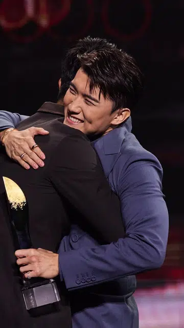 拼图式图片左侧为男艺人张哲通在颁奖典礼舞台上拥抱他人、手持奖座露出笑容；右侧为女艺人黄思恬身穿白色礼服在麦克风前发表感言，身后站着多位手持奖座的女艺人，背景为灯光璀璨的颁奖舞台。