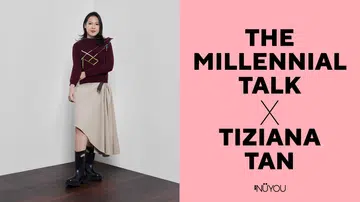 横式杂志封面设计图，画面分为左右两部分。左侧为人物肖像照：一名女性站在简约的白色墙角空间内，地面为深棕色木纹地板；她身穿酒红色针织上衣，上衣带有彩色线条装饰细节，下身搭配米色不对称设计半裙，并穿着黑色中筒厚底靴，整体造型时尚而带有现代感。她神情自然自信，身体微微向前行走，直视镜头。右侧为粉红色背景的文字排版区，以黑色粗体字写着“THE MILLENNIAL TALK × TIZIANA TAN”，下方附有NUYOU杂志标志，整体风格简洁明快，具有时尚人物专访封面氛围。