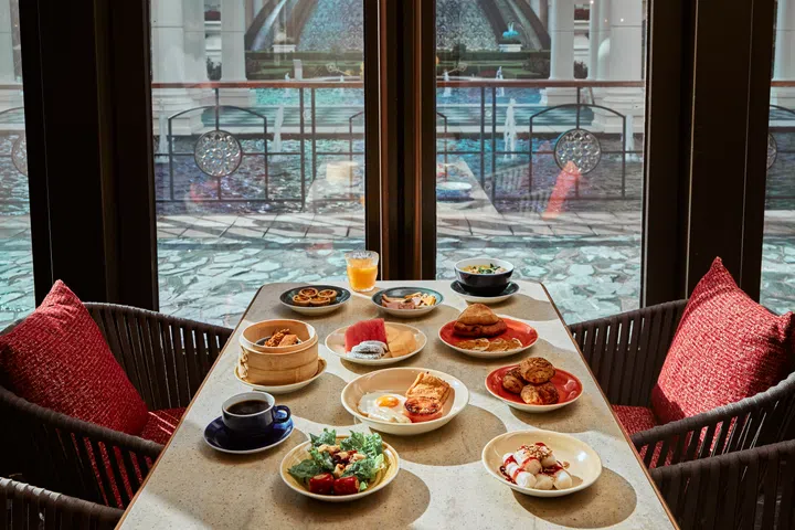 澳门上葡京综合度假村自助山餐厅的早餐餐桌，汇集中西式料理与甜点，搭配窗外的绿意与水景，营造悠闲又疗愈的度假氛围。澳门3天2夜旅游攻略。