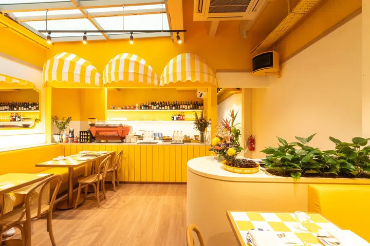Fortuna Terrazza 餐厅室内空间照，整体以明亮黄色为主调，搭配拱形遮棚设计、开放式吧台与整齐排列的餐桌座位，呈现充满阳光感与意式风格的用餐环境，适合好友聚会与轻松用餐。| 新加坡最值得打卡的高颜值聚餐好去处