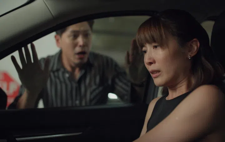 《一路惊魂》剧照。欧萱饰演的刘惠珍坐在车内神情紧张压抑，眼眶泛红，窗外的陈罗密欧焦急拍打车窗，夫妻关系中的矛盾与情绪张力在狭小空间中爆发。