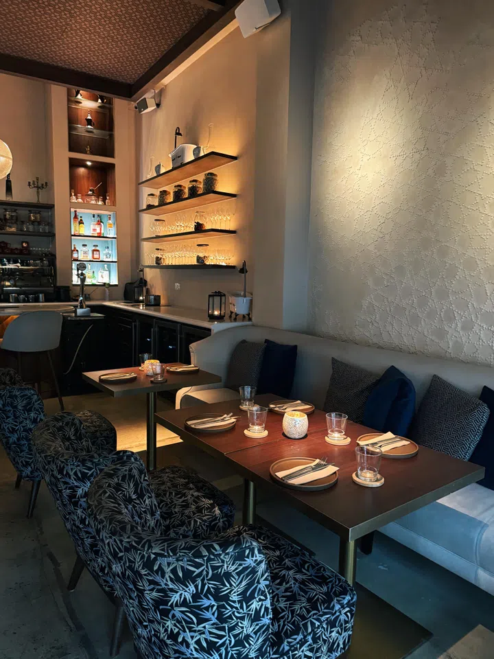 Fat Prince 餐厅室内用餐空间照，画面可见沙发式座位与摆放整齐的餐桌，搭配暖色灯光、开放式吧台与酒架设计，呈现适合好友聚会与小型聚餐的餐厅环境。| 新加坡最值得打卡的高颜值聚餐好去处