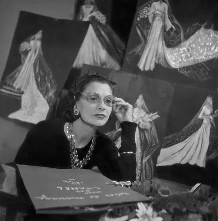 Book cover use of this asset requires approval. Please contact your Account Representative.Mandatory Credit: Photo by Roger Schall/Condé Nast/Shutterstock (11807239a)Designer Coco Chanel wearing large-rimmed glasses surrounded by sketches of her designs. Coco ChanelVogue May 01, 1938 Portrait