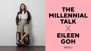 横式杂志封面设计图，画面分为左右两部分。左侧为人物肖像：一名女性站在简约的白色墙角空间内，地面为深棕色木纹地板。她留着中长直发，神情自信从容，直视镜头；身穿白色上衣，外搭深棕色长风衣，下身搭配卡其色高腰短裤，并穿着黑色皮质乐福鞋，整体造型简洁利落、带有都会时尚感。她一脚微微交叉站立，双手自然插在口袋中，呈现沉稳而专业的姿态。右侧为粉红色背景的文字排版区，以黑色粗体字写着“THE MILLENNIAL TALK × EILEEN GOH”，下方附有NUYOU杂志标志，整体风格简约现代，具有时尚人物访谈封面氛围。