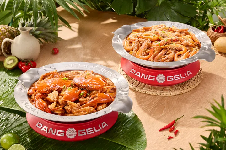 两锅热气腾腾的招牌肉蟹煲与虾煲分别盛装在金属锅中，锅内可见鲜红螃蟹、大虾及鸡爪等食材，搭配浓郁酱汁，色泽诱人。锅具置于红色炉座上，周围点缀青柠、辣椒与热带植物元素，营造丰盛与活力的用餐氛围，呈现适合新春期间与家人好友共享的丰富海鲜佳肴与聚餐选择。新加坡大年初一初二照常营业餐厅推荐：8家不打烊好去处（2026马年）