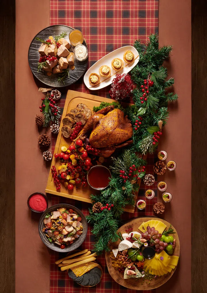 一桌 Rasel Catering 的圣诞自助餐料理以红绿节日色系呈现，包括烤火鸡、烤蔬菜、甜点塔、奶酪拼盘、冷盘沙拉与节庆小点，周围点缀松果、浆果与圣诞花饰，营造温馨节日气氛。圣诞大餐吃什么？新加坡9家必订自助餐全攻略