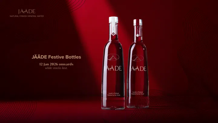 JÄÄDE新年限定节庆瓶装展示图。画面以深红色为背景，两瓶750ml玻璃瓶装JÄÄDE气泡水与纯净水并排陈列，瓶身设计简约优雅，搭配银白色瓶盖与节庆限定标签，整体呈现北欧极简风格与新春氛围结合的高级质感，适合作为新年送礼或餐桌摆设的清新饮品礼。2026马年新年送礼推荐：拜年礼盒与新年礼物精选